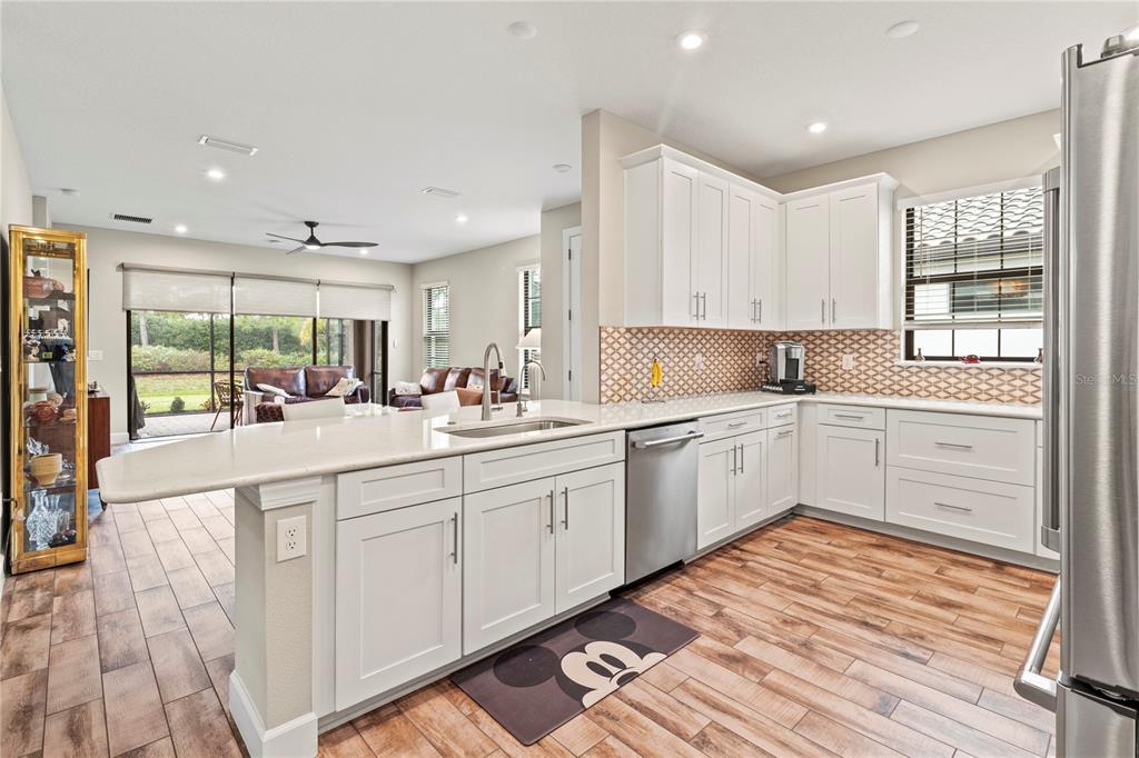 A kitchen with white cabinets, quartz countertops, stainless steel appliances, and wood-look tile flooring — 14655 DERNA TERRACE, BRADENTON, FL