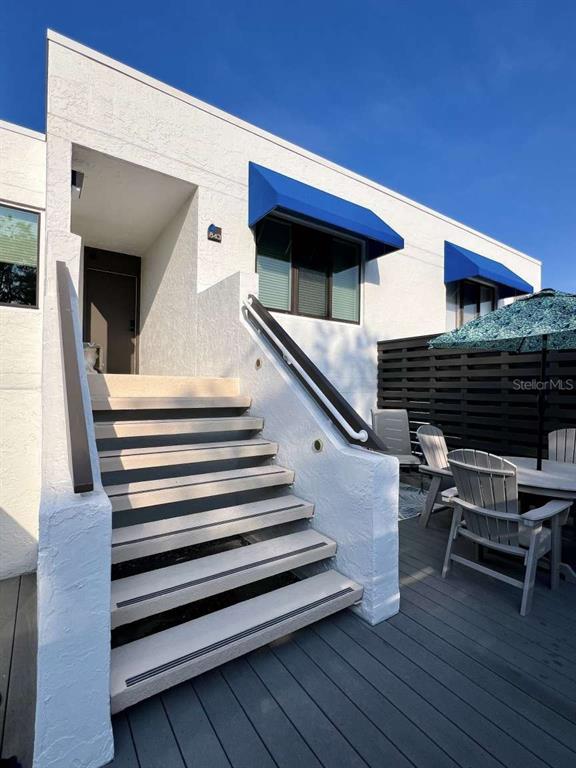 An exterior view shows a white building with blue awnings, stairs, and a patio area — 843 BAYPORT WAY UNIT 843, LONGBOAT KEY, FL