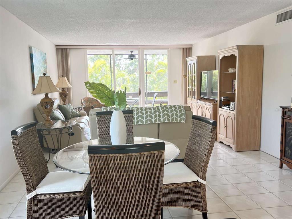 A dining area with a glass table and wicker chairs overlooks a living room — 843 BAYPORT WAY UNIT 843, LONGBOAT KEY, FL