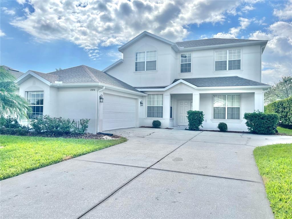 A two-story house with a white stucco exterior, a garage, and a concrete driveway — 2370 HINSDALE DRIVE, KISSIMMEE, FL