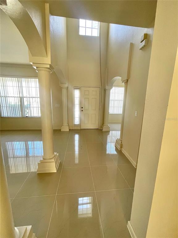 A bright entryway features high ceilings, tiled floors, white columns, and a front door — 2370 HINSDALE DRIVE, KISSIMMEE, FL