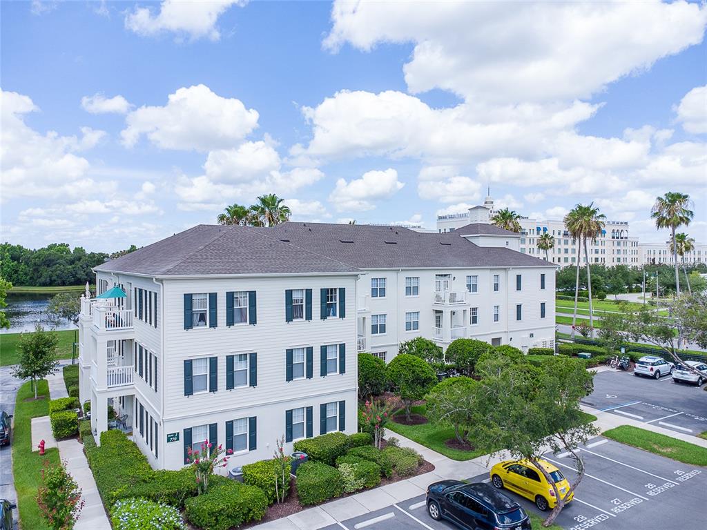 An exterior view of a multi-story apartment building with a parking lot and pond — 770 SIENA PALM DRIVE UNIT 206, CELEBRATION, FL