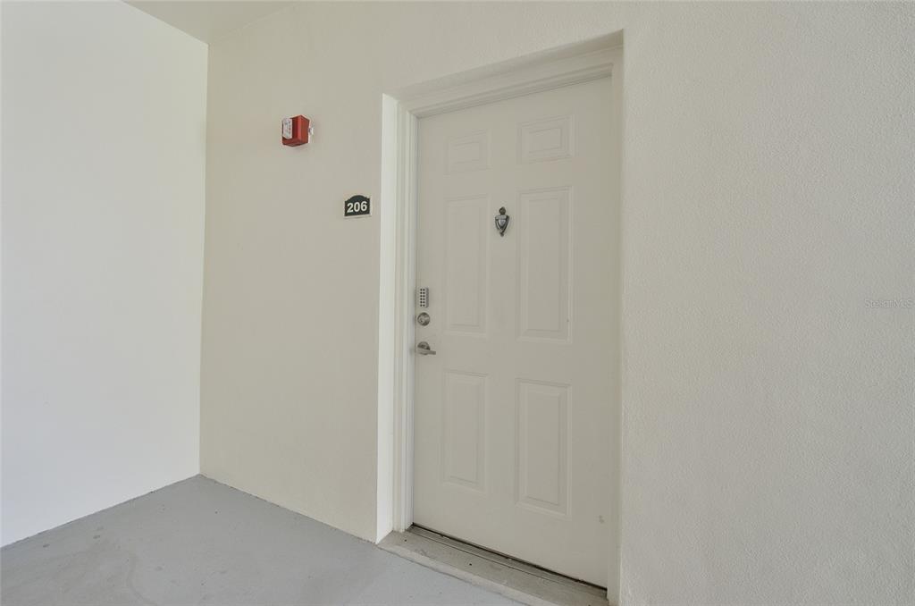 A white exterior door with a digital lock and a unit number sign 206 — 770 SIENA PALM DRIVE UNIT 206, CELEBRATION, FL
