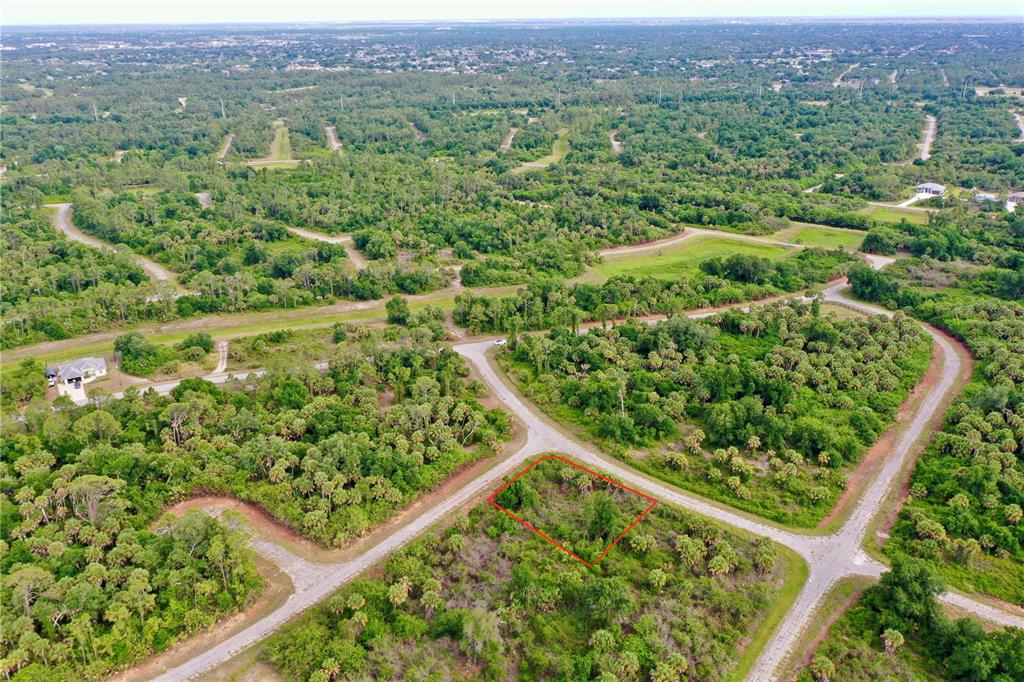 An aerial view shows a vacant, rectangular lot outlined in red within a wooded neighborhood — HEARST STREET, NORTH PORT, FL
