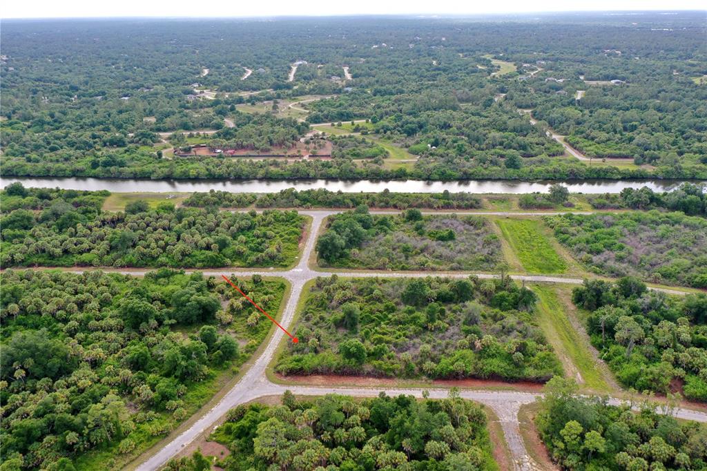 An aerial view shows a vacant, wooded lot marked by a red arrow near roads — HEARST STREET, NORTH PORT, FL