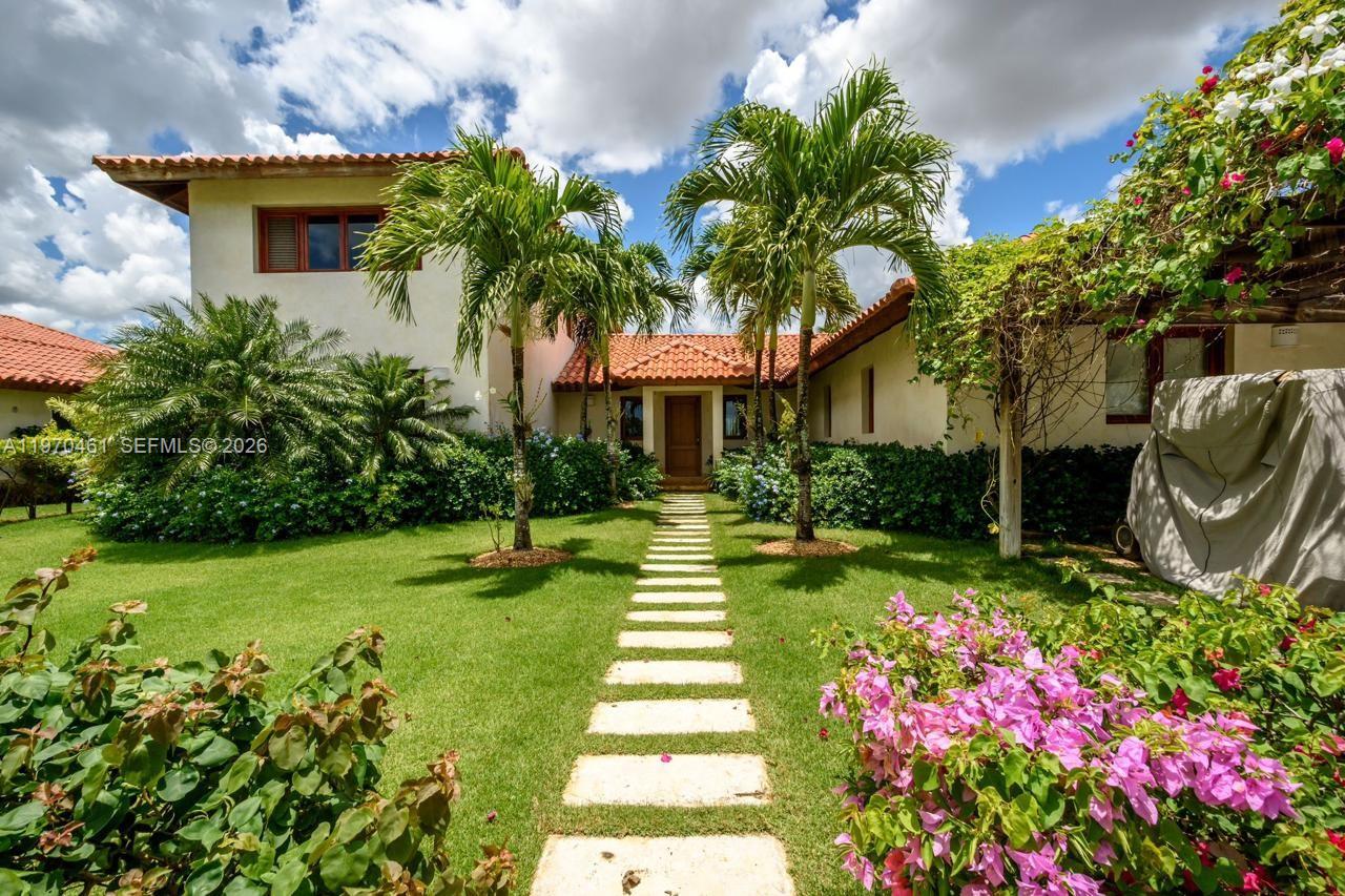 A stone path leads through a grassy yard to the entrance of a two-story house — Los Robles 8, La Estancia Golf Resort, DR, DR
