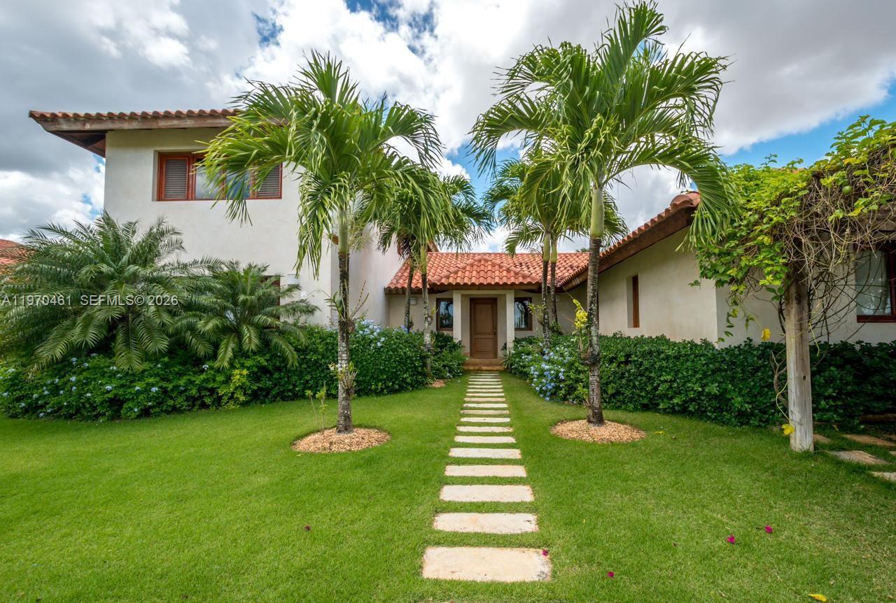 A two-story house with a tiled roof, palm trees, and a stone walkway in front — Los Robles 8, La Estancia Golf Resort, DR, DR
