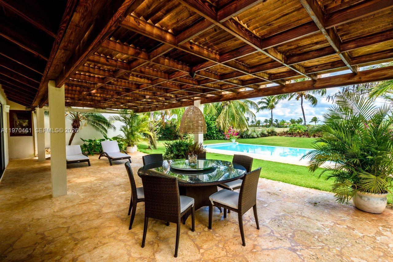 A covered patio features a dining set, lounge chairs, and a view of a pool — Los Robles 8, La Estancia Golf Resort, DR, DR