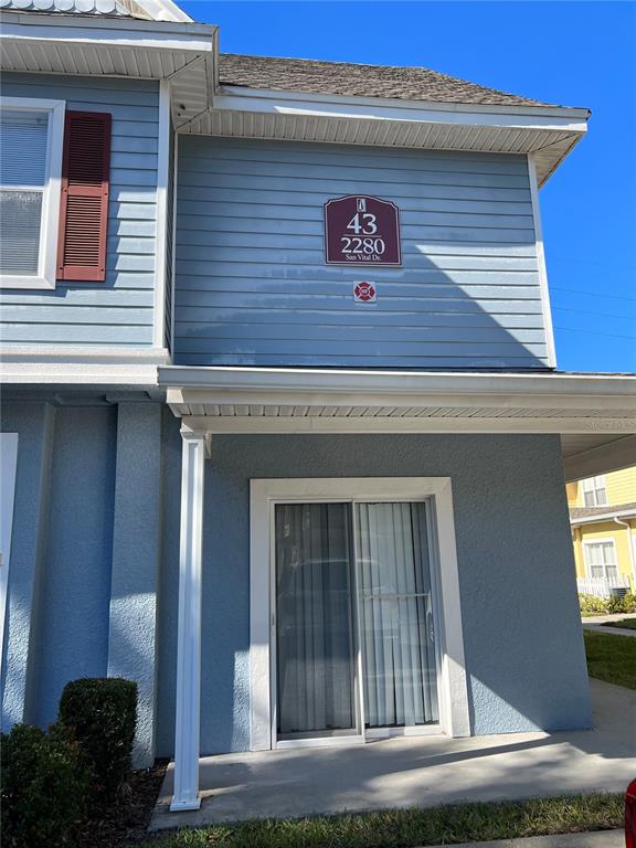 A blue two-story building exterior features a sliding glass door entrance and a unit sign — 2280 SAN VITAL DRIVE UNIT 107, KISSIMMEE, FL