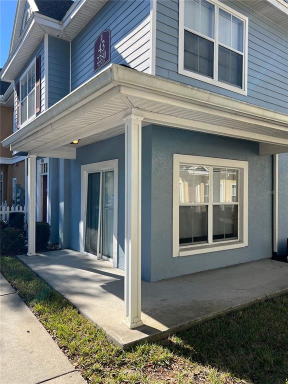 A blue two-story building features a covered concrete patio with white columns and siding — 2280 SAN VITAL DRIVE UNIT 107, KISSIMMEE, FL