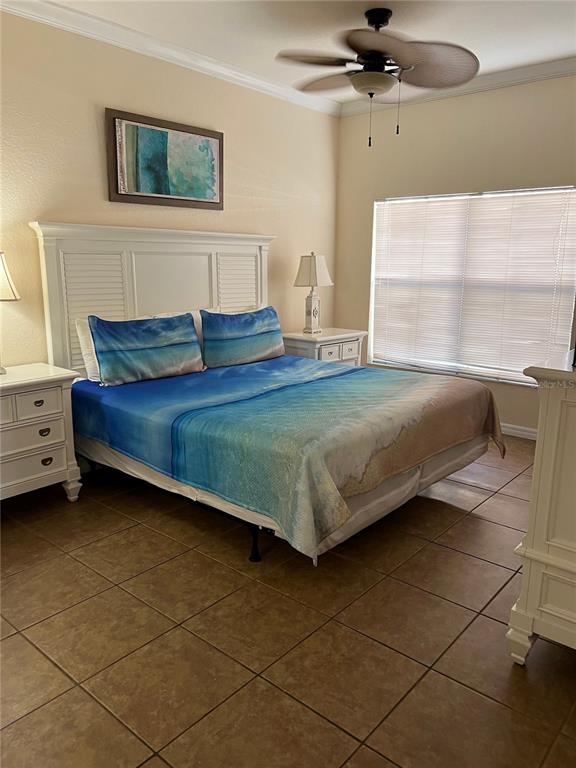 A bedroom features a bed with beach-themed bedding, a white headboard, and tile flooring — 2280 SAN VITAL DRIVE UNIT 107, KISSIMMEE, FL