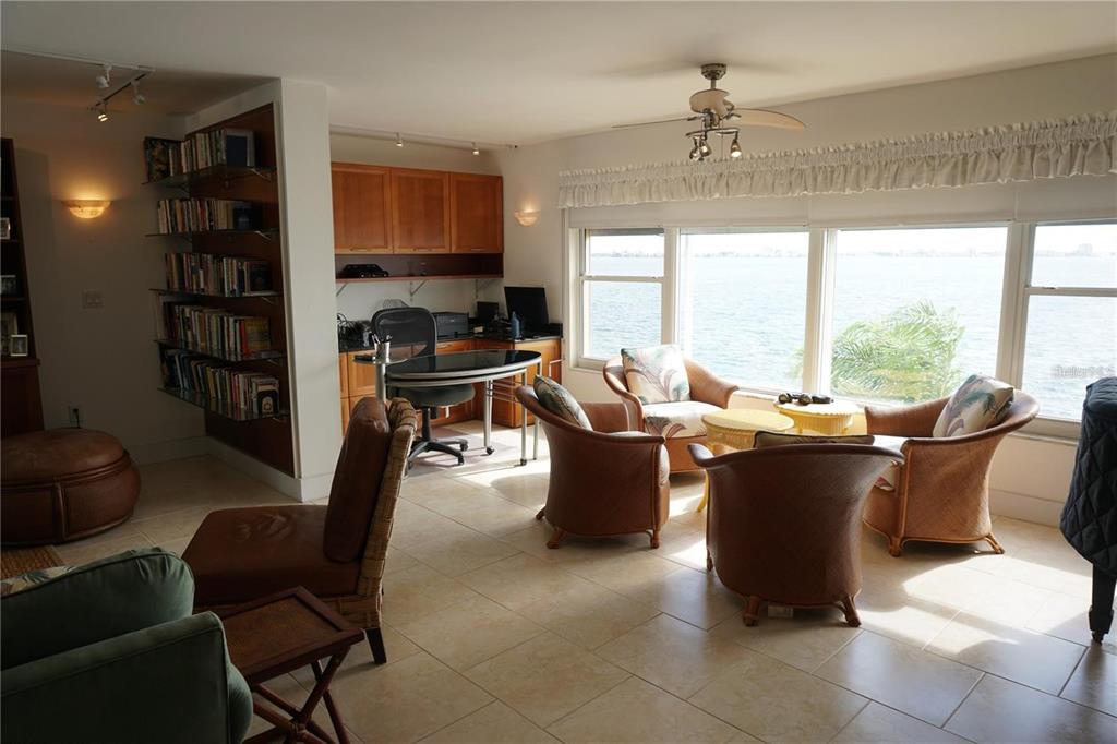 A living area with a home office, tile floors, and large windows overlooking the water — 5900 SHORE BOULEVARD S UNIT 402, GULFPORT, FL