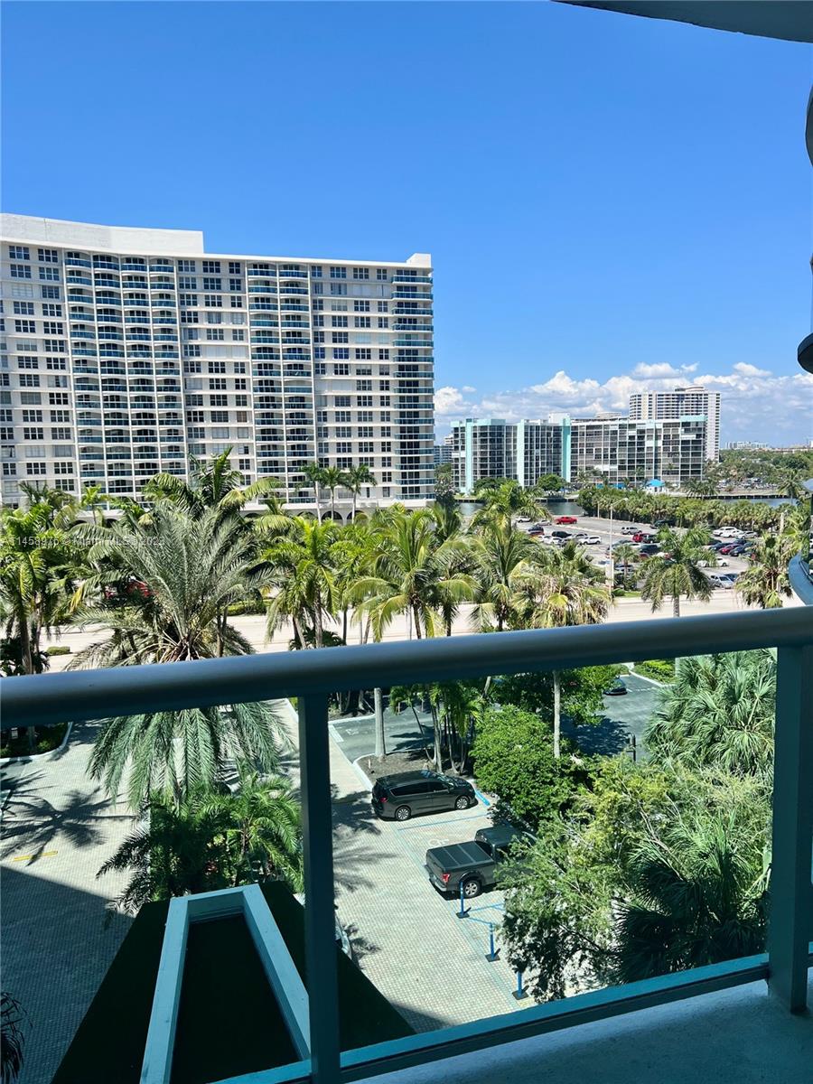 A balcony view overlooking a parking lot, palm trees, and large residential apartment buildings — 3801 S Ocean Dr # 6S, Hollywood FL 33019, HOLLYWOOD, FL