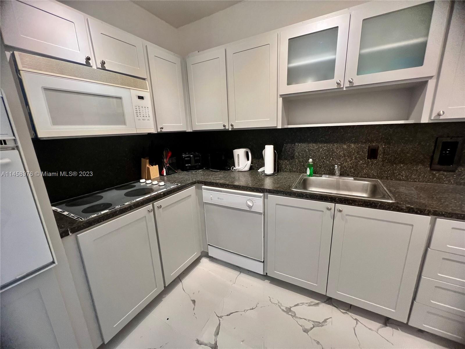 A kitchen features light gray cabinets, dark countertops, stainless steel appliances, and white marble-patterned flooring — 3801 S Ocean Dr # 6S, Hollywood FL 33019, HOLLYWOOD, FL