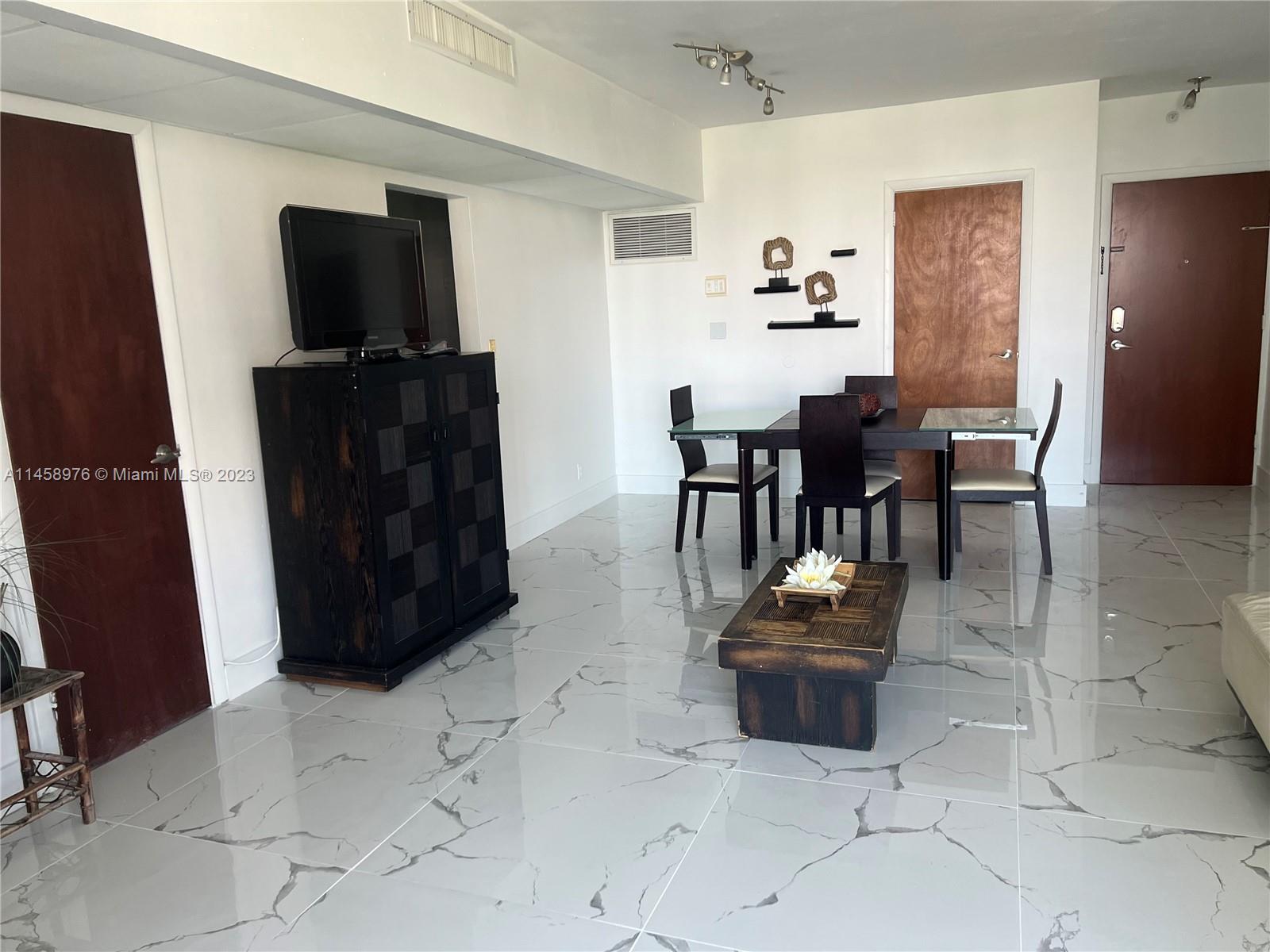 A dining and living area features white marble-look tile flooring and dark wood furniture — 3801 S Ocean Dr # 6S, Hollywood FL 33019, HOLLYWOOD, FL