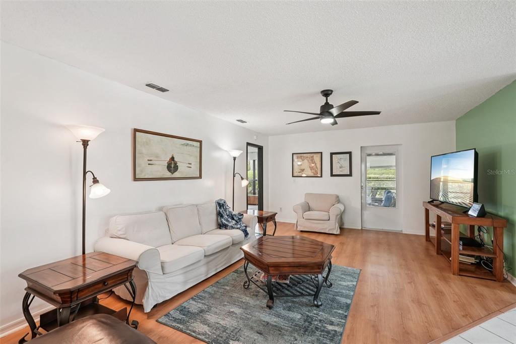 A living room features a white sofa, a hexagonal coffee table, and a television stand — 1604 LELAND DRIVE, SUN CITY CENTER, FL