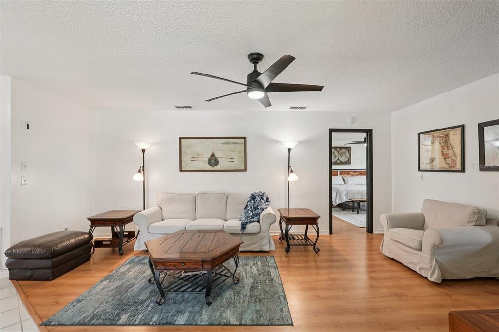 A living room features a white sofa, armchair, wooden coffee table, and a ceiling fan — 1604 LELAND DRIVE, SUN CITY CENTER, FL