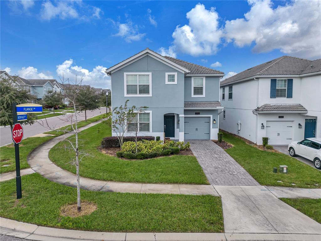 A two-story light blue house with a brick driveway and a single-car garage — 1592 FLANGE DRIVE, DAVENPORT, FL