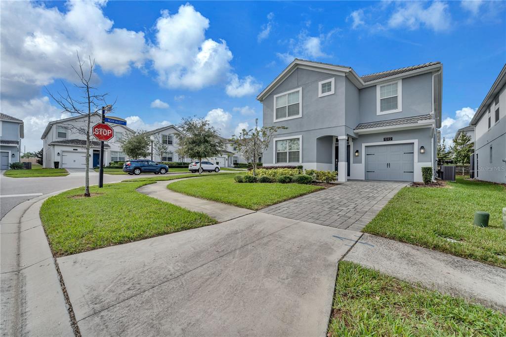 A two-story gray house with a paved driveway and a front lawn under a blue sky — 1592 FLANGE DRIVE, DAVENPORT, FL