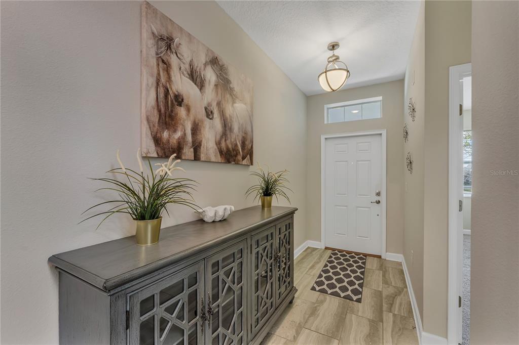 A foyer features a gray console table, horse wall art, and a white front door — 1592 FLANGE DRIVE, DAVENPORT, FL