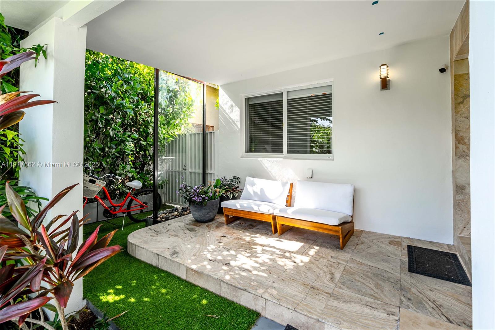 A covered patio features a stone floor, two wooden chairs, and an adjacent artificial grass area — 1360 SW 16th St, Miami FL 33145, MIAMI, FL