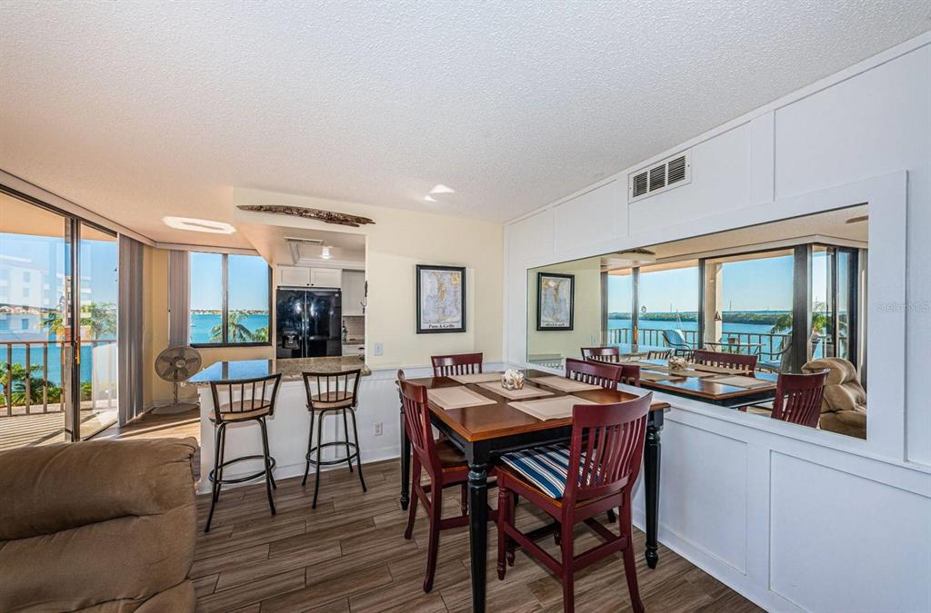 A dining area with a wooden table, chairs, and a large mirror overlooking a balcony — 6357 BAHIA DEL MAR BOULEVARD UNIT 408, ST PETERSBURG, FL