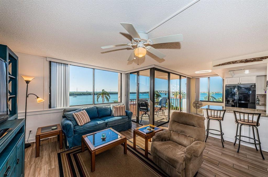 A living room with a blue sofa, brown recliner, and views of the water — 6357 BAHIA DEL MAR BOULEVARD UNIT 408, ST PETERSBURG, FL