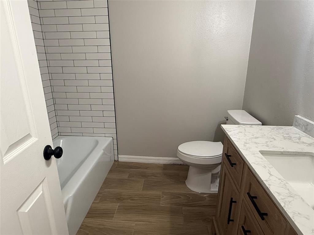 A bathroom features a white bathtub with subway tile, a toilet, and a wood vanity — 1008 N BRACEWELL DRIVE, PLANT CITY, FL