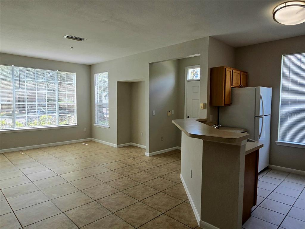 A kitchen with a breakfast bar overlooks an open living area with tiled floors — 9005 LEE VISTA BLVD UNIT 1803, ORLANDO, FL