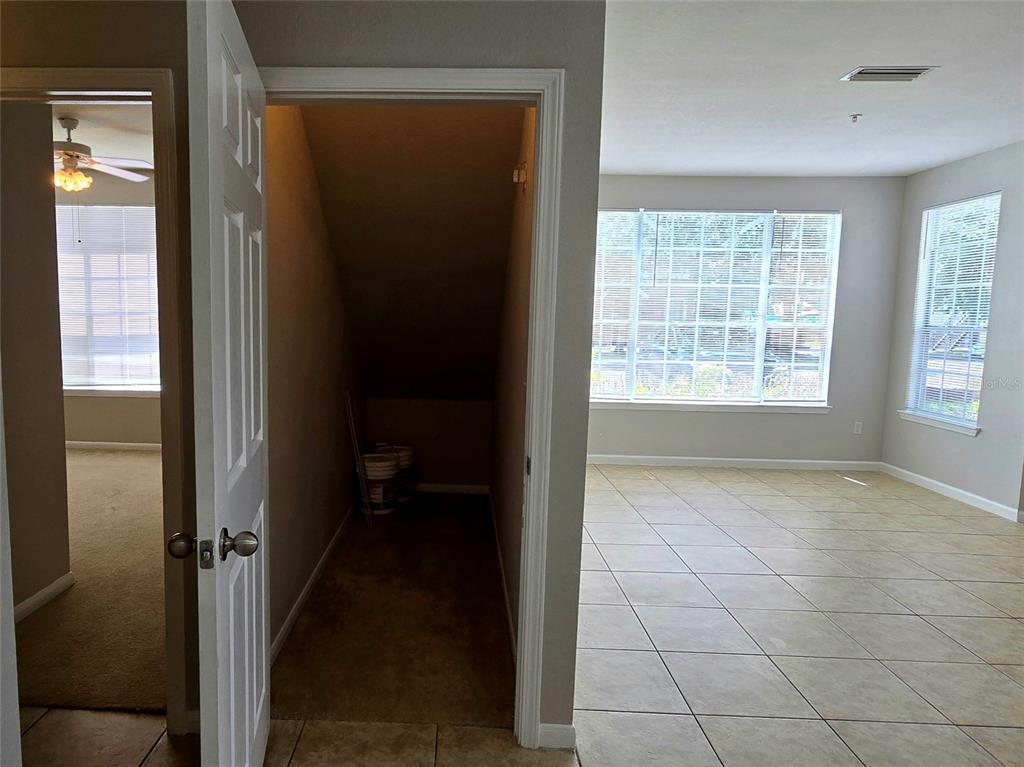 A view of a tiled living area with a storage closet under the stairs — 9005 LEE VISTA BLVD UNIT 1803, ORLANDO, FL