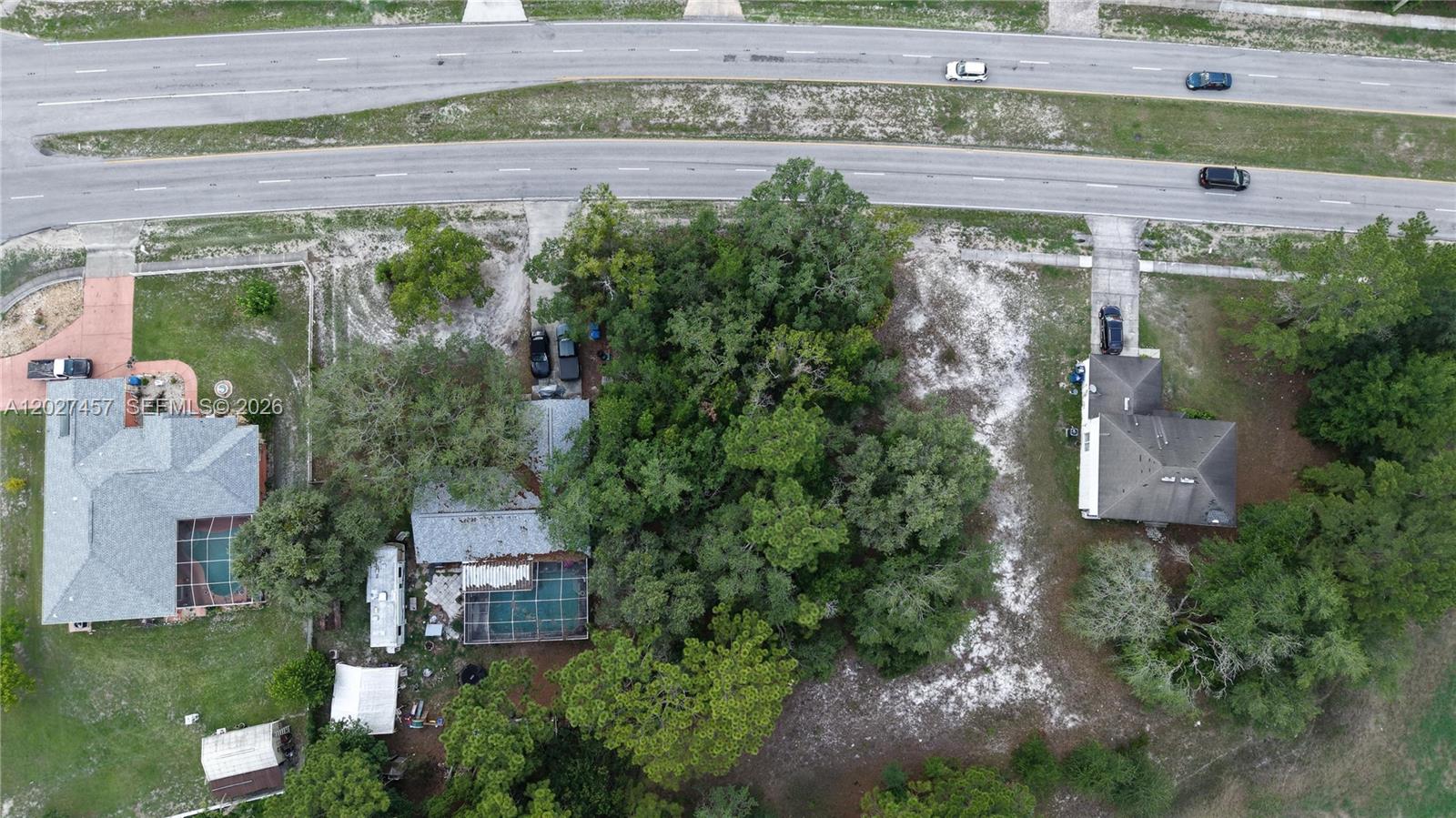 An aerial view shows two houses separated by a dense cluster of trees — 4164 DELTONA BLVD, Spring Hill FL 34606, SPRING HILL, FL