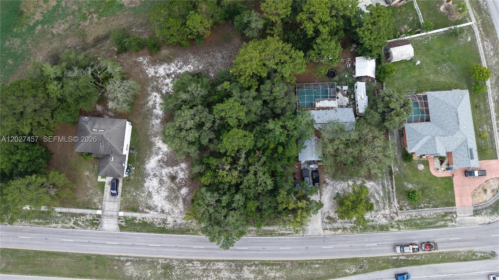 An aerial view shows three houses separated by wooded areas along a paved road — 4164 DELTONA BLVD, Spring Hill FL 34606, SPRING HILL, FL