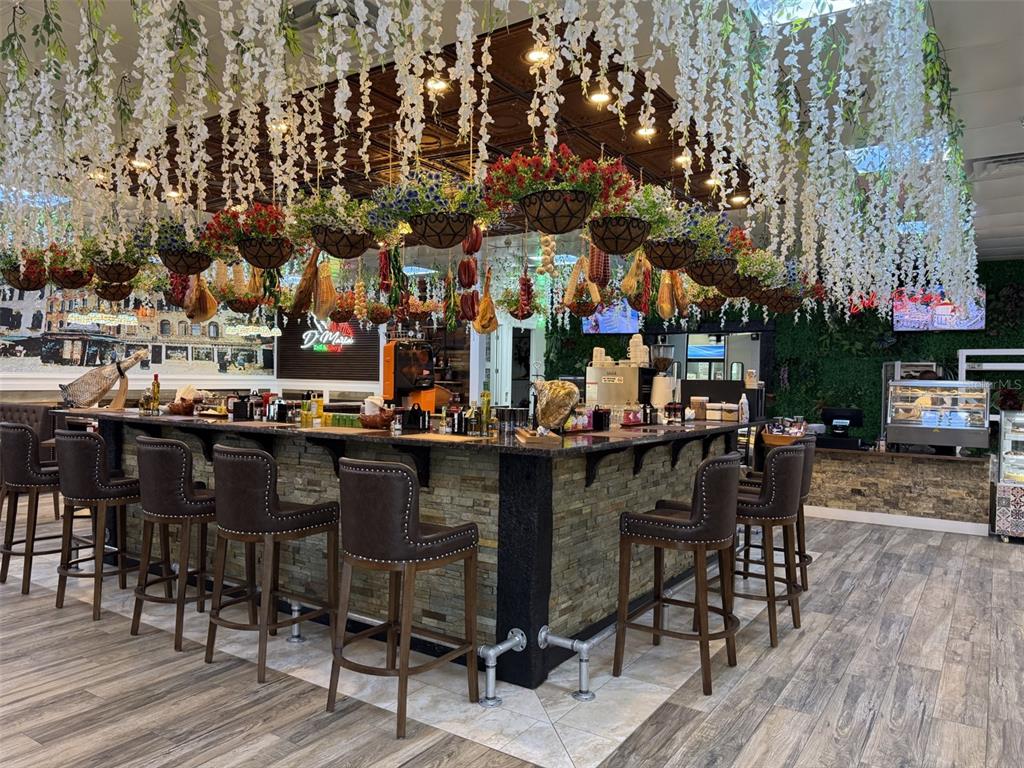 A restaurant bar features stone siding, hanging floral decorations, and brown leather stools — 4984 PALM COAST NW PARKWAY, PALM COAST, FL