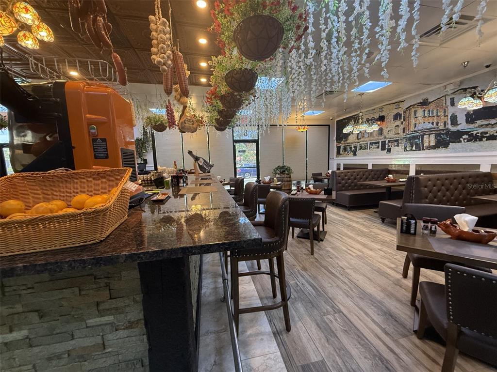 This restaurant interior features a granite bar, hanging floral decor, and brown leather booth seating — 4984 PALM COAST NW PARKWAY, PALM COAST, FL