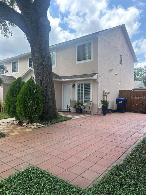 A two-story stucco townhouse features a large tree, a paved patio, and a front entrance — 6738 MAGNOLIA POINTE CIRCLE, ORLANDO, FL