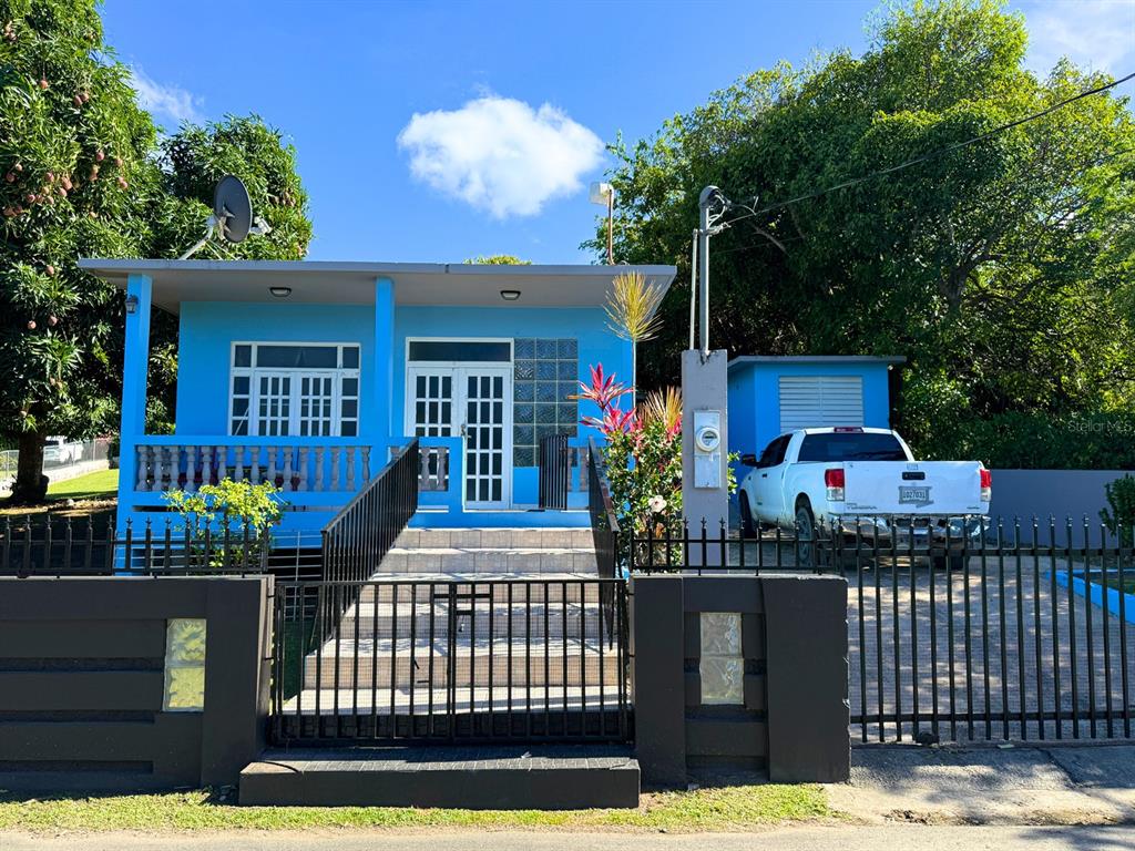 A bright blue house with a front porch, metal fence, and a white pickup truck parked — 120 CALLE 16, VIEQUES, PR