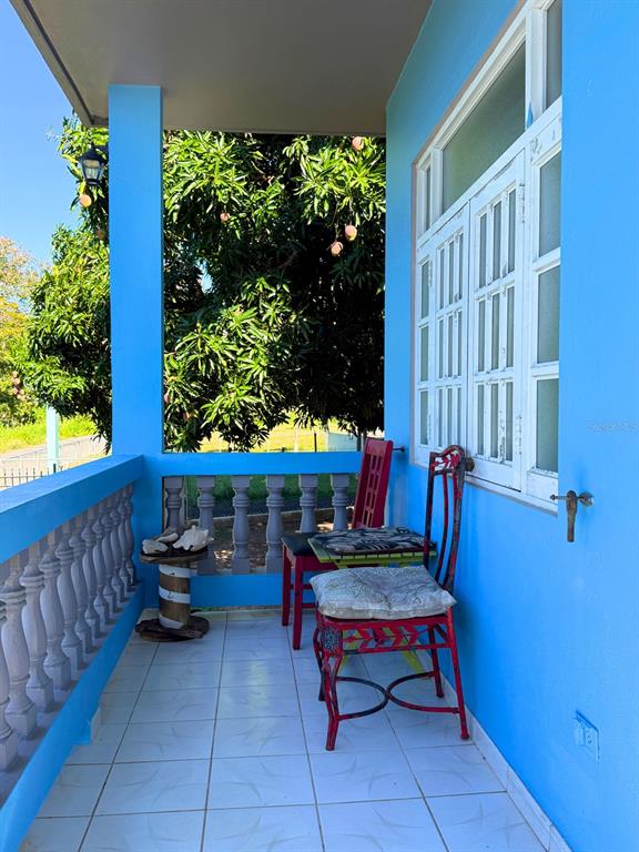 A bright blue porch features tiled flooring, a decorative railing, and two metal chairs — 120 CALLE 16, VIEQUES, PR