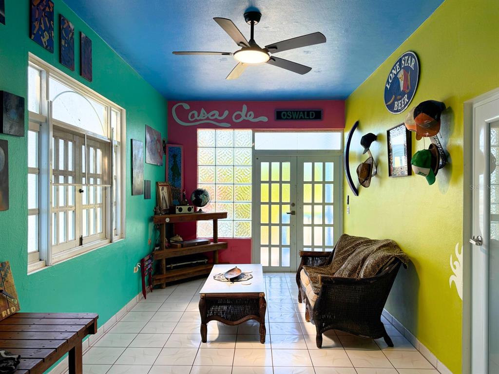 A sunroom features colorful walls, a ceiling fan, tile flooring, and a wicker sofa — 120 CALLE 16, VIEQUES, PR