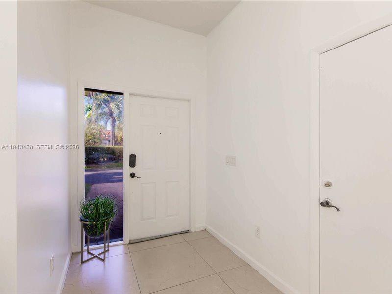 An entryway features a white front door, a side window, and light-colored tile flooring — 21475 SW 90th Pl, Cutler Bay FL 33189, CUTLER BAY, FL