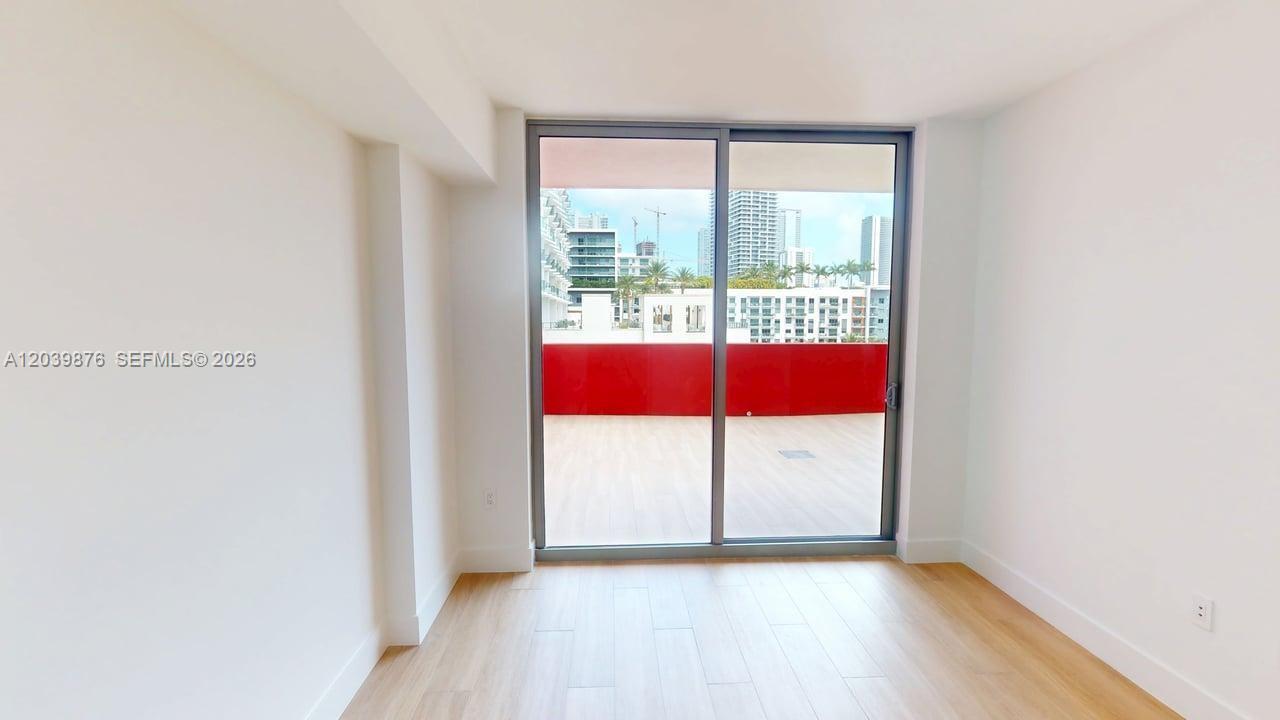 A room with light wood flooring and a sliding glass door leading to a balcony — 90 NE 32nd Street # 603, Miami FL 33127, MIAMI, FL