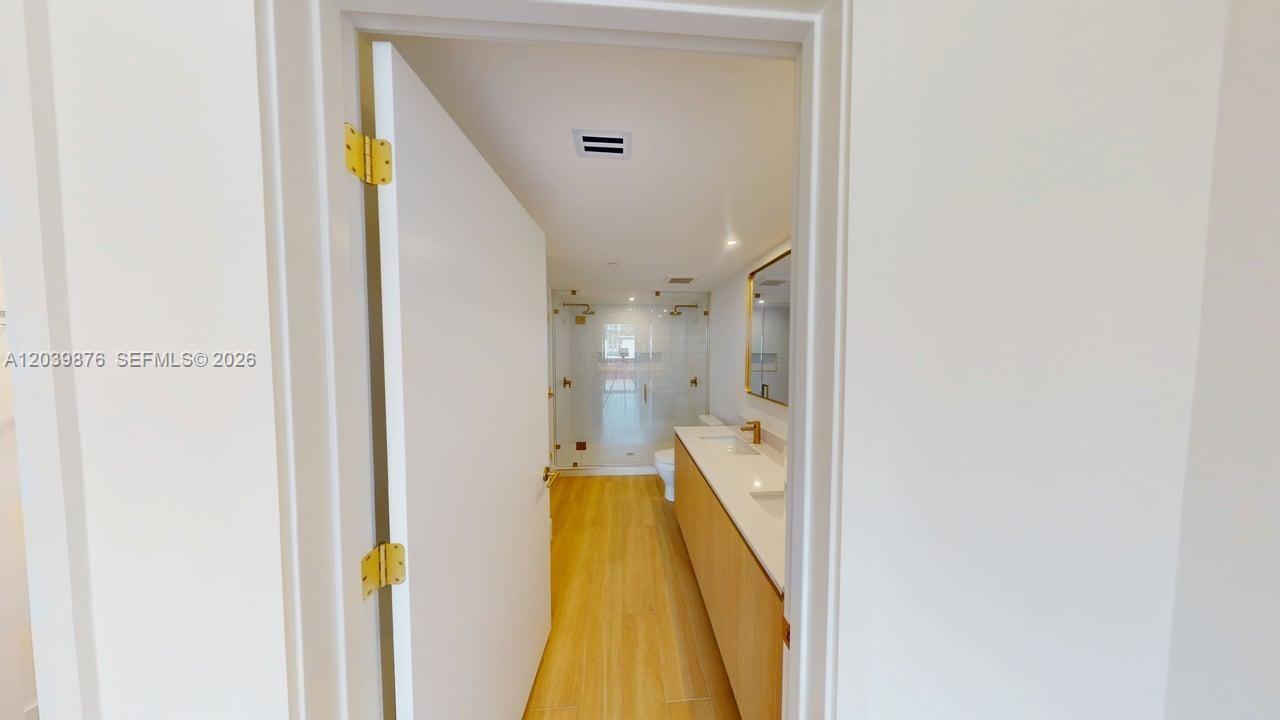 A bathroom features a double vanity with gold fixtures, wood-look flooring, and a glass shower — 90 NE 32nd Street # 603, Miami FL 33127, MIAMI, FL