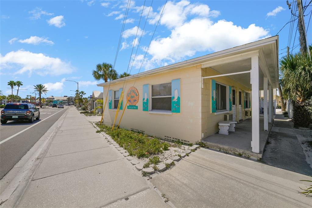 A single-story yellow apartment building with a covered porch sits along a sidewalk — 13062 GULF BOULEVARD, MADEIRA BEACH, FL