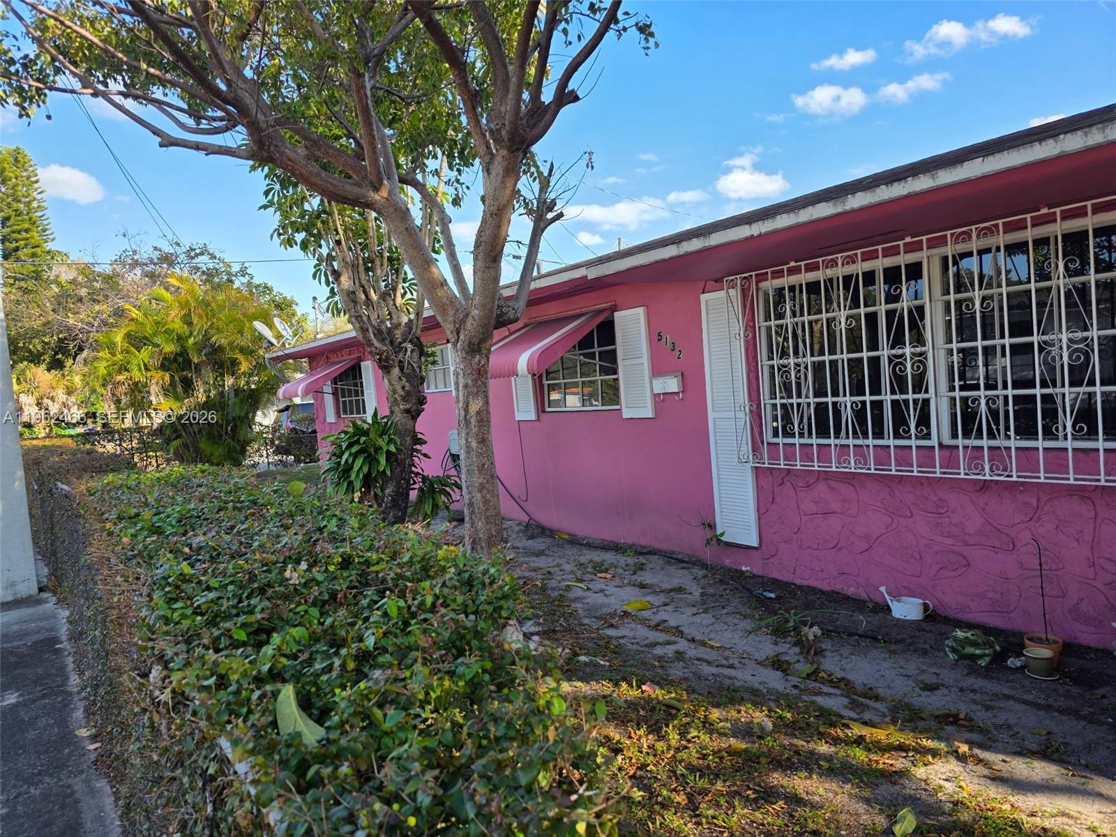 A pink single-story house features white window security bars and striped awnings — 5132 NW 14th Ave, Miami FL 33142, MIAMI, FL