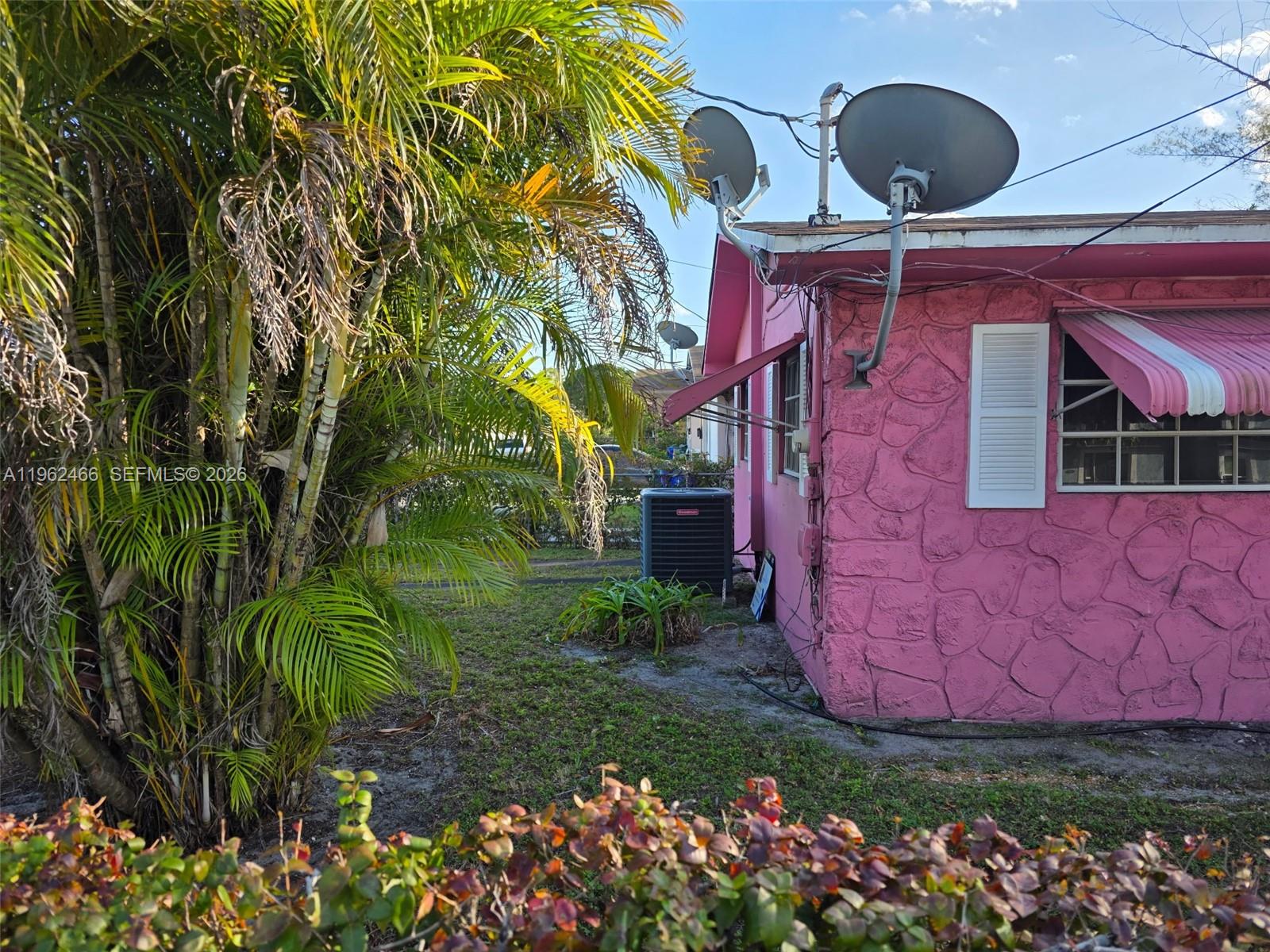 A pink house with stone-textured siding features two satellite dishes and a window awning — 5132 NW 14th Ave, Miami FL 33142, MIAMI, FL
