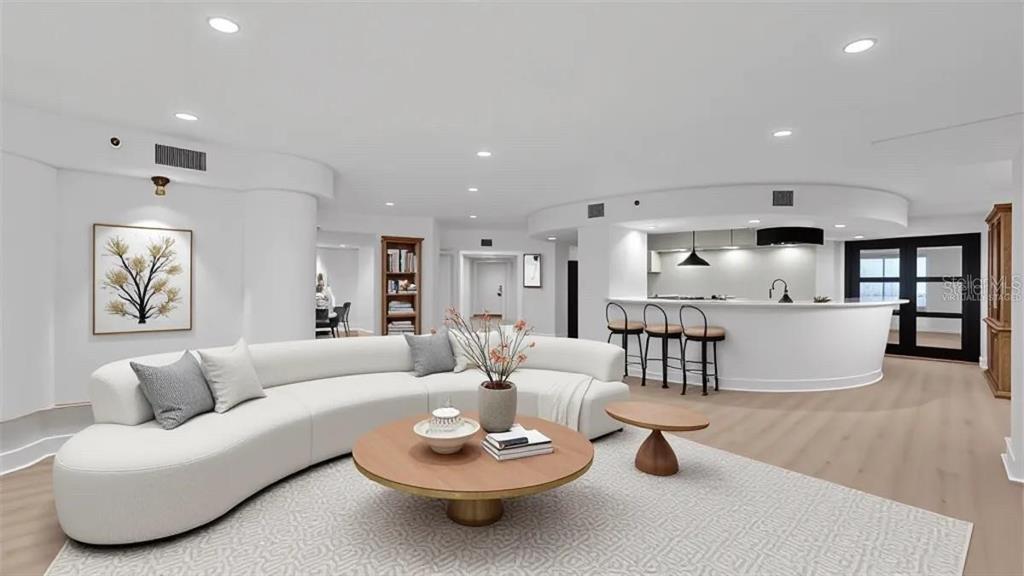 This is a virtually staged living room with a curved sofa, coffee table, and kitchen bar — 400 E COLONIAL DRIVE UNIT 1606, ORLANDO, FL