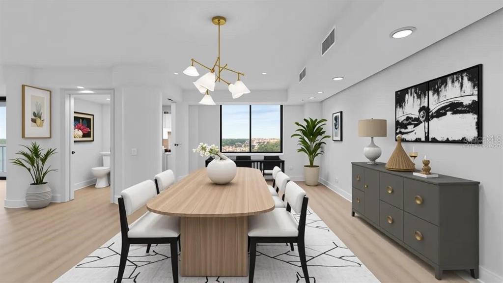 This dining room features a wooden table, white chairs, a modern chandelier, and light flooring — 400 E COLONIAL DRIVE UNIT 1606, ORLANDO, FL