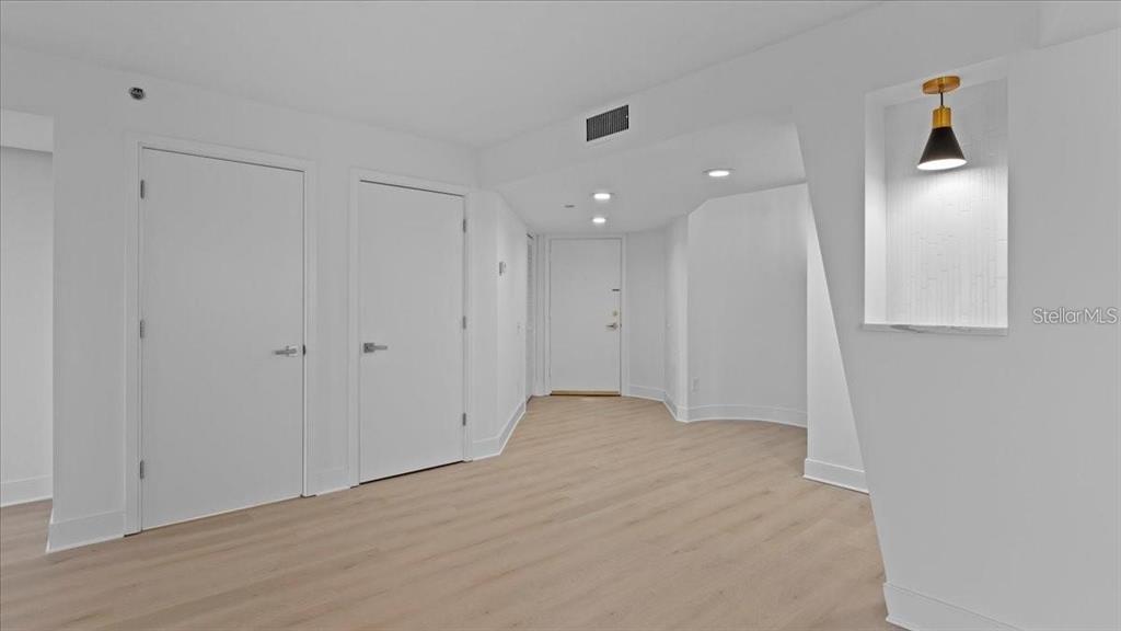 A minimalist hallway features light wood flooring, white walls, and a recessed wall niche — 400 E COLONIAL DRIVE UNIT 1606, ORLANDO, FL
