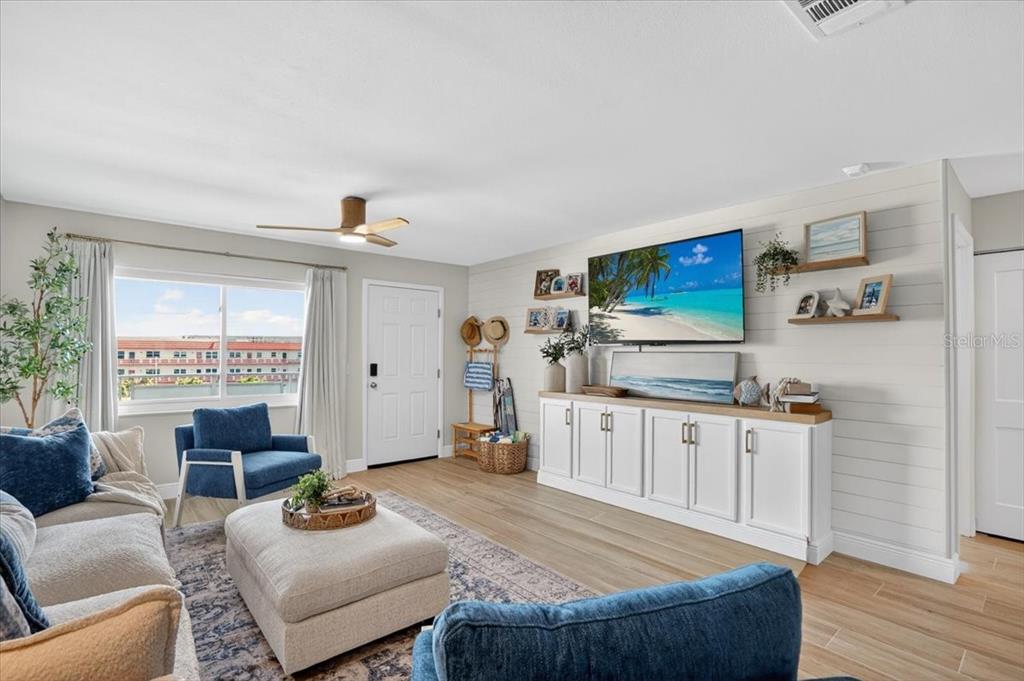 A bright living room features shiplap walls, a ceiling fan, and blue accent furniture — 2960 59TH STREET S UNIT 310, GULFPORT, FL