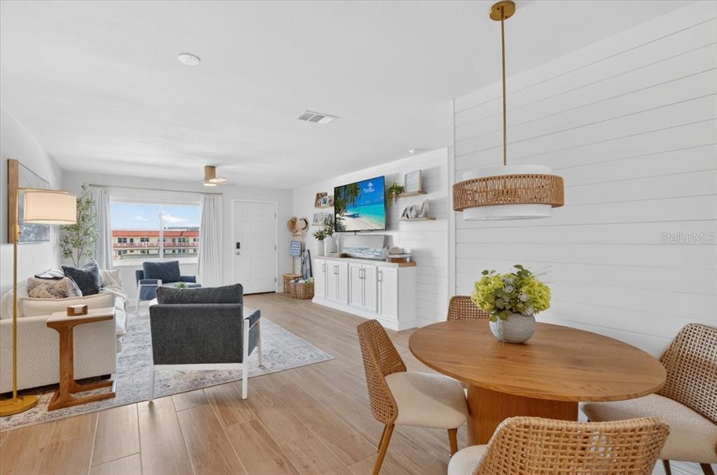A living room features a white media console, a wall-mounted television, and blue accent furniture — 2960 59TH STREET S UNIT 310, GULFPORT, FL