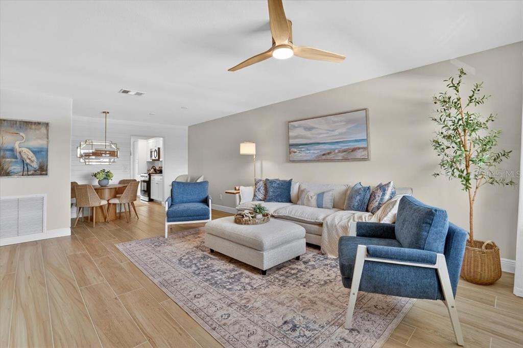 A bright open-concept living and dining area features wood-look flooring and a shiplap accent wall — 2960 59TH STREET S UNIT 310, GULFPORT, FL